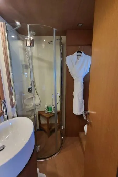 Slide: The Image of Das Bild zeigt ein elegantes Badezimmer auf einer Yacht mit einer runden Duschkabine und einem Waschbecken. - 23