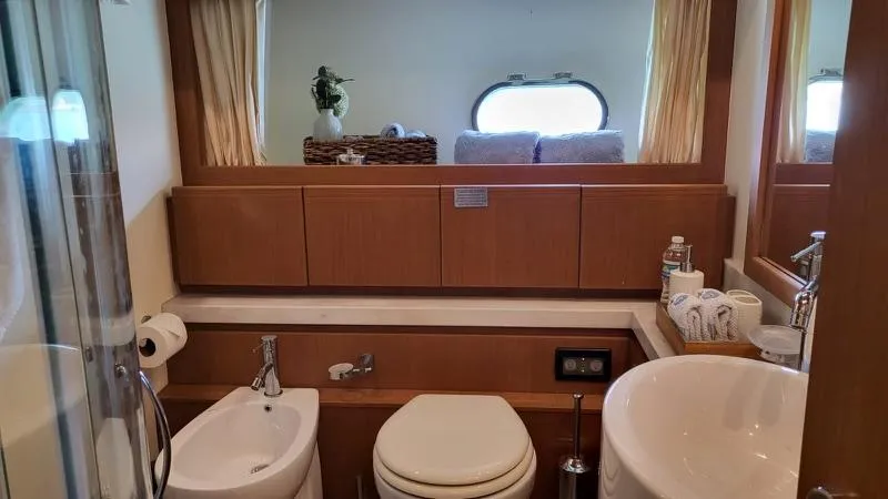 Slide: The Image of Ein elegantes Badezimmer mit Holzverkleidung, Waschbecken, Toilette und Bidet. Ein Fenster bietet Tageslicht. - 26