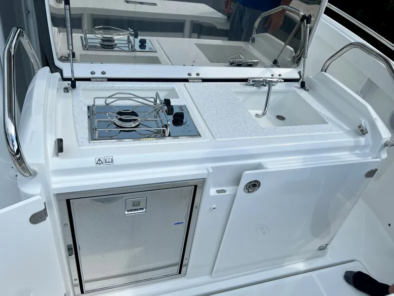 Slide: The Image of 2024 Jeanneau Leader 9.0 CC boat kitchen with stove, sink, and storage. - 21