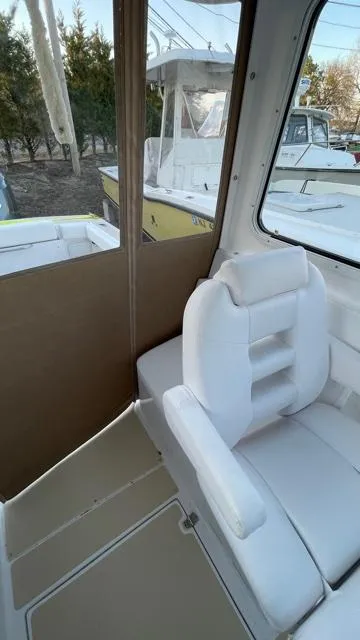 Slide: The Image of 2022 NorthCoast 235 HT boat interior with white seating and window view. - 14