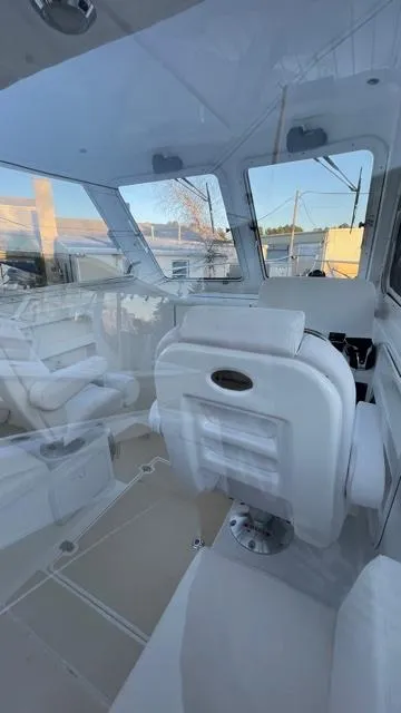 Slide: The Image of 2022 NorthCoast 235 HT boat interior with white seating and large windows. - 18