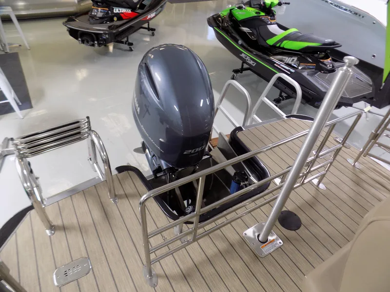Slide: The Image of 2022 Sylvan L3 DLZ pontoon boat with outboard motor and jet skis in showroom. - 5