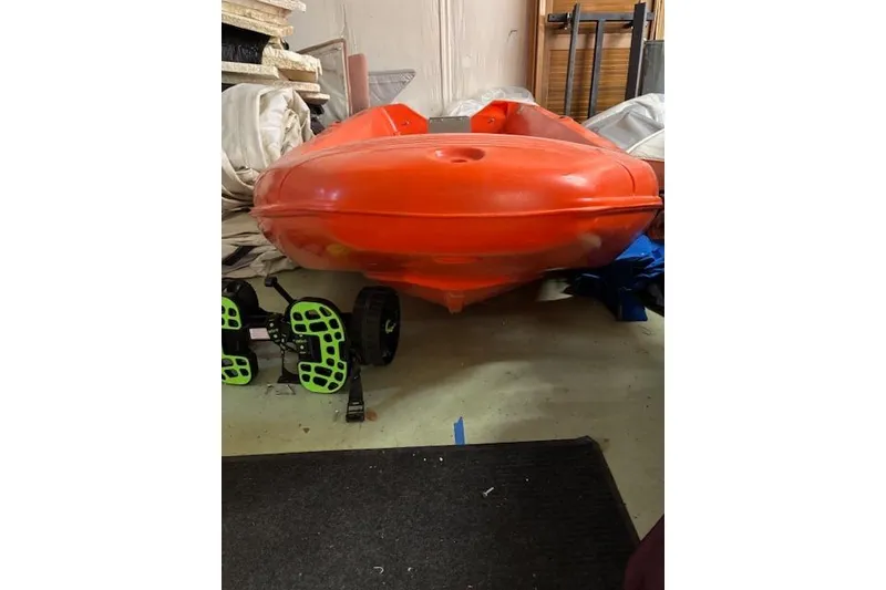 Slide: The Image of Bright orange River Boats 350 kayak, 2022 model, stored indoors with equipment nearby. - 4