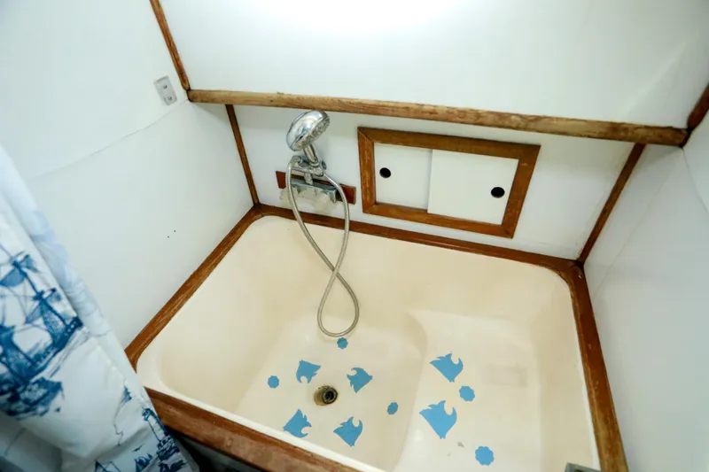 Slide: The Image of 1979 Sea Ranger 37 boat shower with handheld showerhead and nautical-themed curtain. - 26