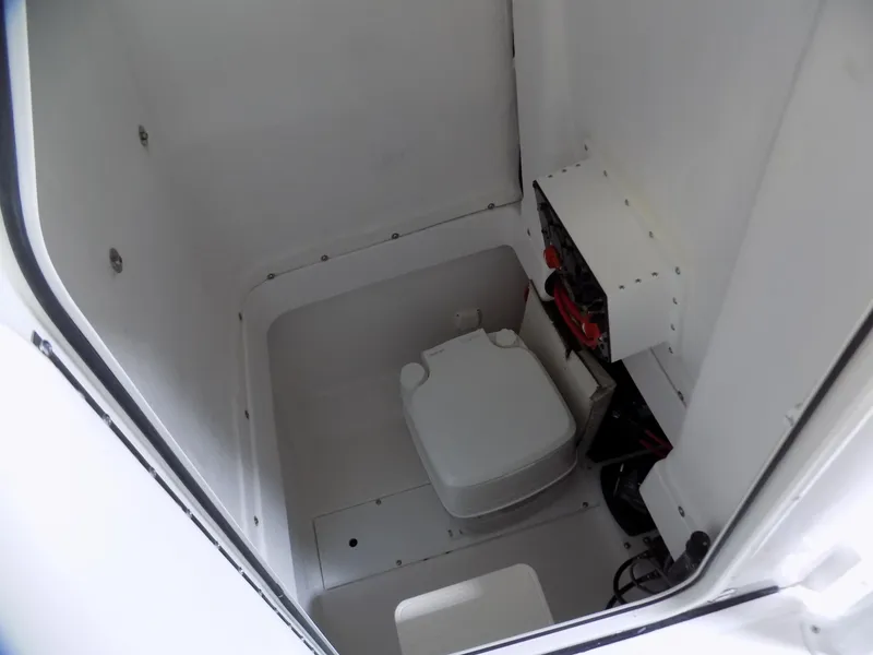 Slide: The Image of 2022 Aquasport 2500 boat interior with compact marine toilet and storage area. - 3