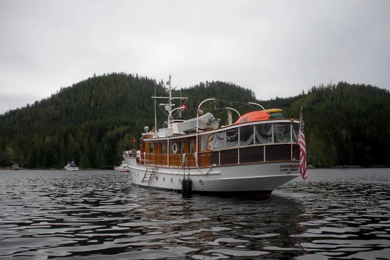Slide: The Image of 1929 Custom HOFFAR-BEECHING Fantail Yacht on a serene lake with forested hills. - 15