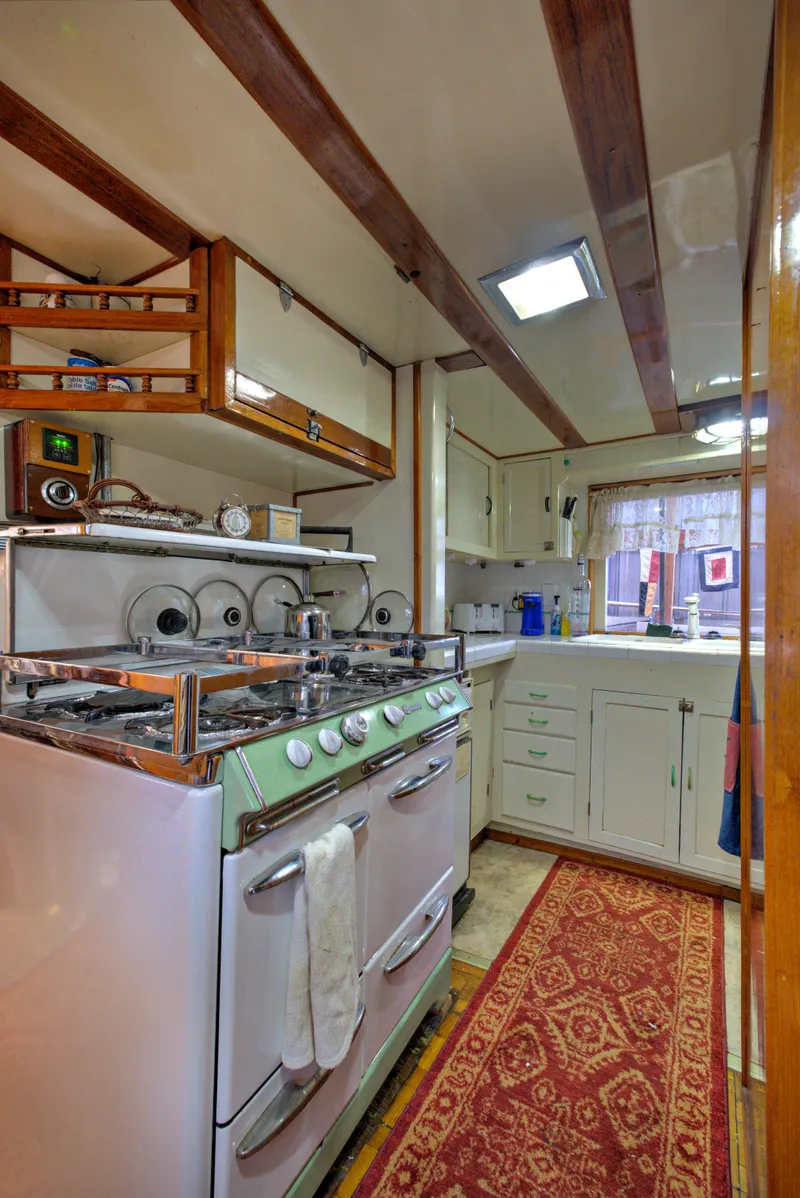Slide: The Image of 1929 HOFFAR-BEECHING Fantail Yacht kitchen with vintage stove and wooden cabinetry. - 44
