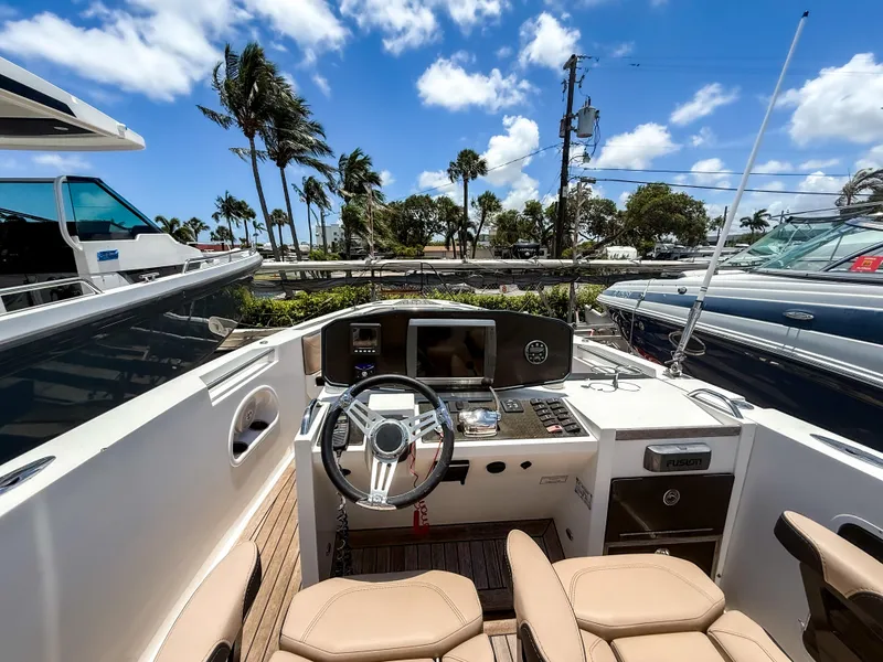 Slide: The Image of 2011 Novurania Chase 23 boat cockpit with steering wheel, dashboard, and seating under clear blue sky. - 8