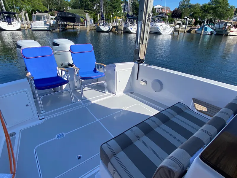 Slide: The Image of 2023 True North 34 Outboard Express boat with blue chairs and striped seating at a marina. - 12
