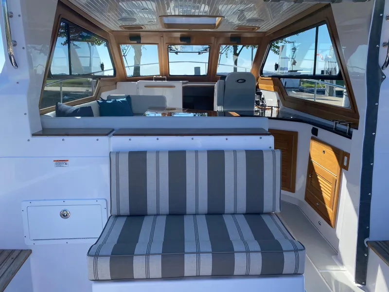 Slide: The Image of 2023 True North 34 Outboard Express interior with striped seating and wooden accents. - 13
