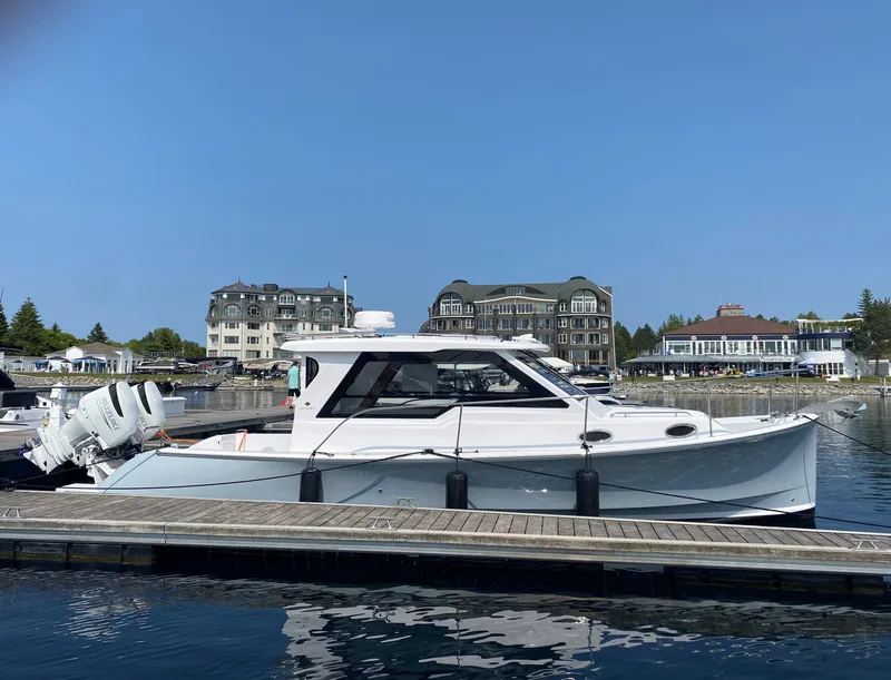 Slide: The Image of 2023 True North 34 Outboard Express docked at marina with scenic waterfront buildings. - 2