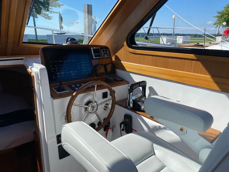 Slide: The Image of 2023 True North 34 Outboard Express helm with wooden accents and modern controls. - 21