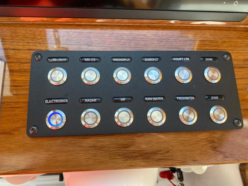 Slide: The Image of Control panel of 2023 True North 34 Outboard Express with labeled buttons on wooden surface. - 23