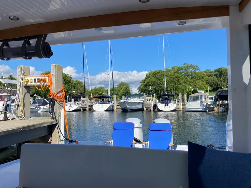 Slide: The Image of 2023 True North 34 Outboard Express docked at a marina with boats and clear blue sky. - 37