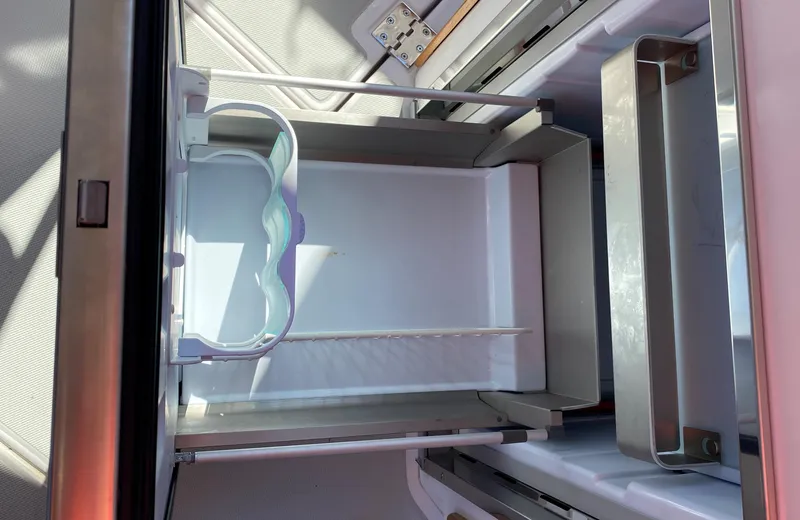 Slide: The Image of Open refrigerator inside 2023 True North 34 Outboard Express boat, showcasing storage compartments. - 45