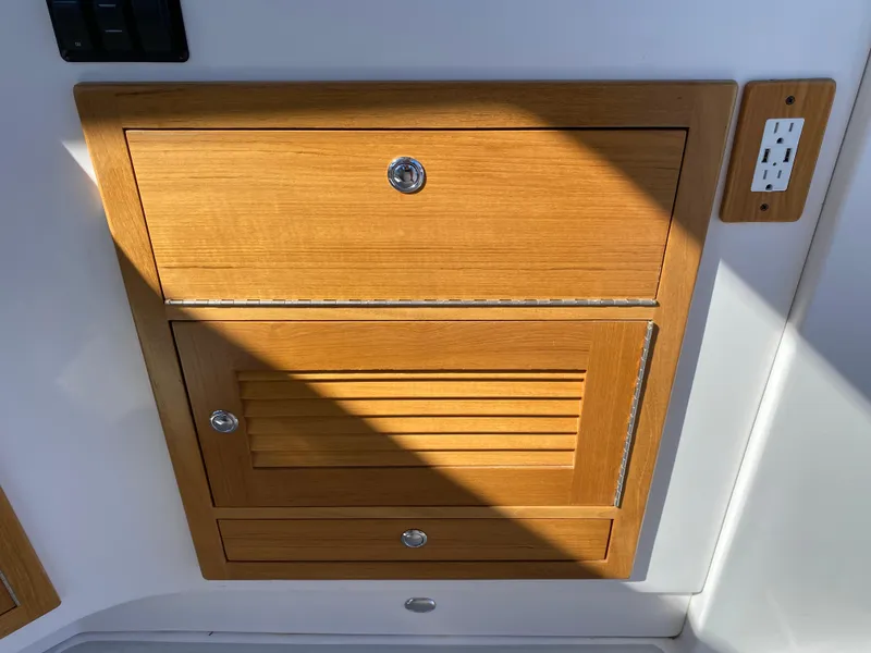 Slide: The Image of Wooden cabinet and electrical outlet on 2023 True North 34 Outboard Express boat interior. - 47