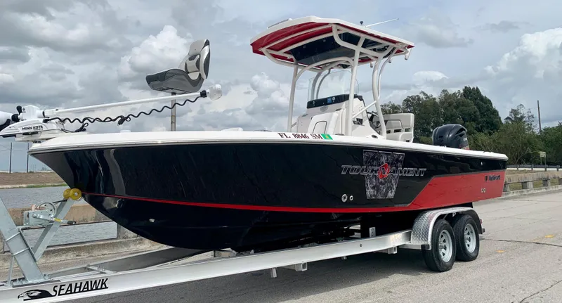 Slide: The Image of 2019 Wellcraft 241 Bay boat on Seahawk trailer, black and red hull, docked. - 4