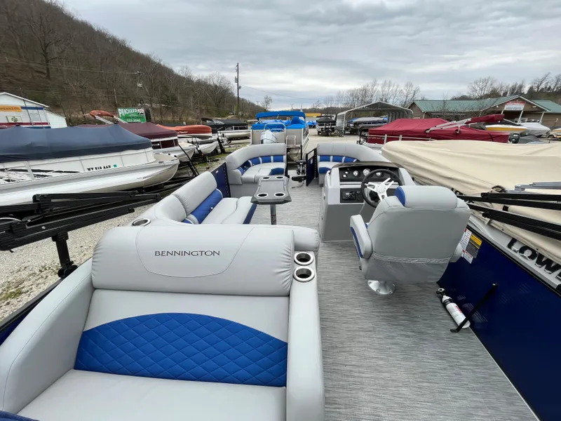 Slide: The Image of 2021 Bennington 22 SSLXP pontoon boat with blue and gray interior at a marina. - 11