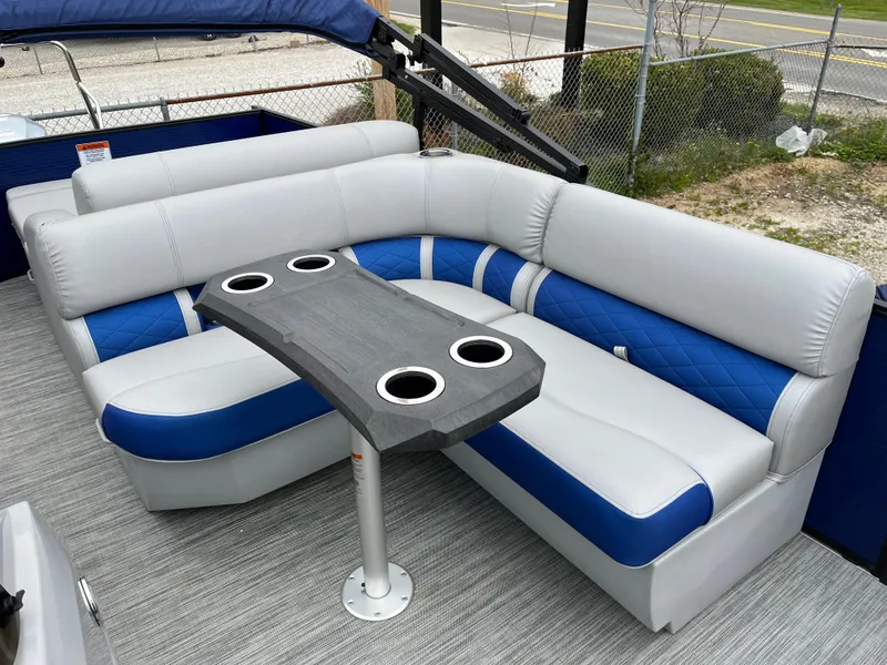Slide: The Image of 2021 Bennington 22 SSLXP boat interior with gray and blue seating and a table with cup holders. - 7