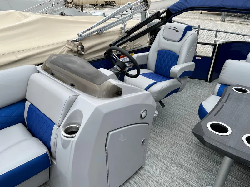 Slide: The Image of 2021 Bennington 22 SSLXP boat interior with blue and white seating, steering console, and cup holders. - 8