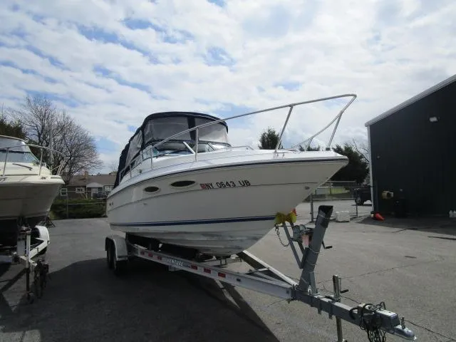 The Image of 1989 Sea Ray 230 Cuddy boat on a trailer in a parking lot. - 1