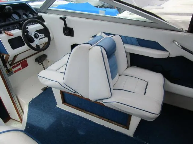 Slide: The Image of 1989 Sea Ray 230 Cuddy interior with white and blue seating, steering wheel, and dashboard. - 10