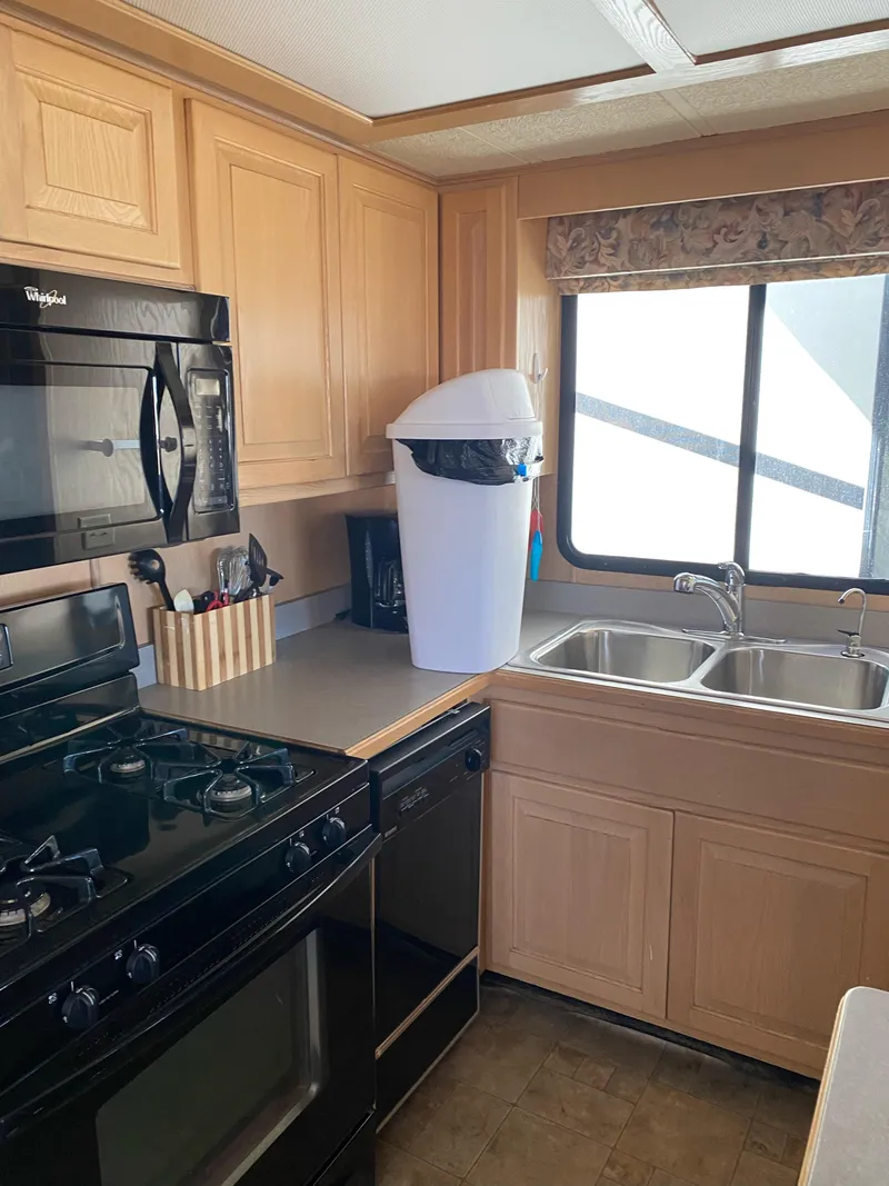 Slide: The Image of 2001 Stardust Cruisers kitchen with wooden cabinets, black appliances, and dual sink. - 22