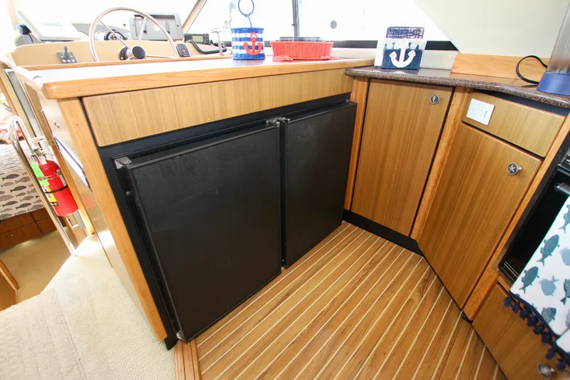 Slide: The Image of 2002 Bayliner 3988 Command Bridge Motoryacht interior with wooden cabinetry and dual black fridge. - 37