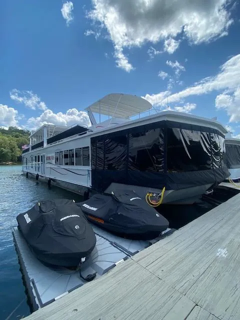 Slide: The Image of 2006 Fantasy houseboat docked with jet skis under a partly cloudy sky. - 2