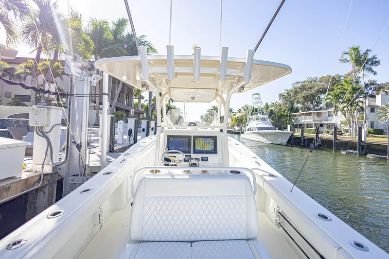 Slide: The Image of 2015 Yellowfin 32 Offshore boat docked in a sunny marina with palm trees. - 11
