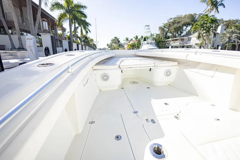 Slide: The Image of 2015 Yellowfin 32 Offshore boat interior with white seating and palm trees in the background. - 22