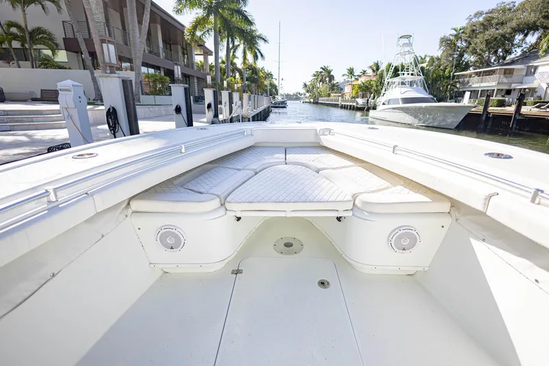 Slide: The Image of 2015 Yellowfin 32 Offshore boat interior with cushioned seating, docked in a scenic canal. - 24