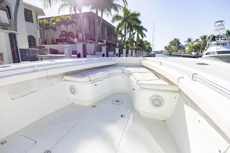 Slide: The Image of 2015 Yellowfin 32 Offshore boat interior with white seating, docked near palm trees. - 26