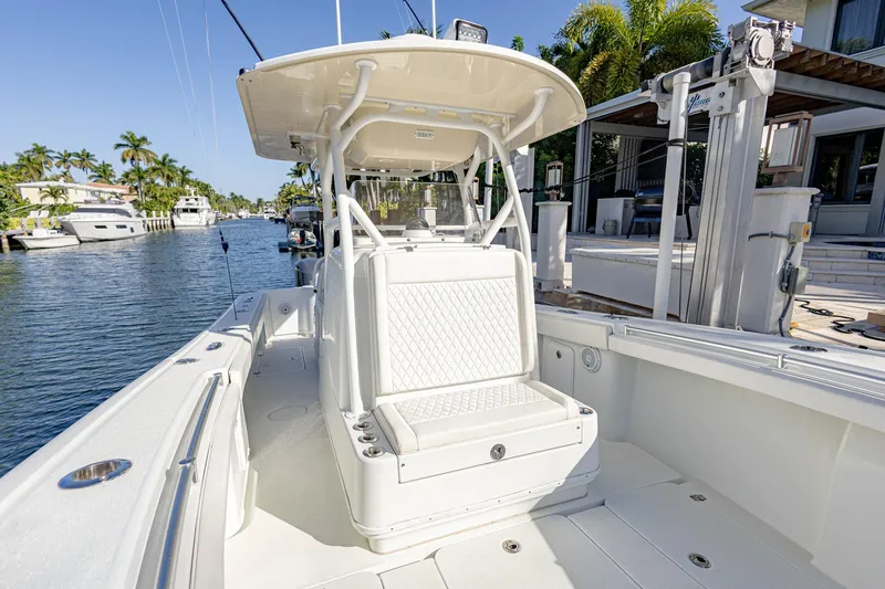 Slide: The Image of 2015 Yellowfin 32 Offshore boat docked by waterfront homes, featuring spacious seating and sleek design. - 5