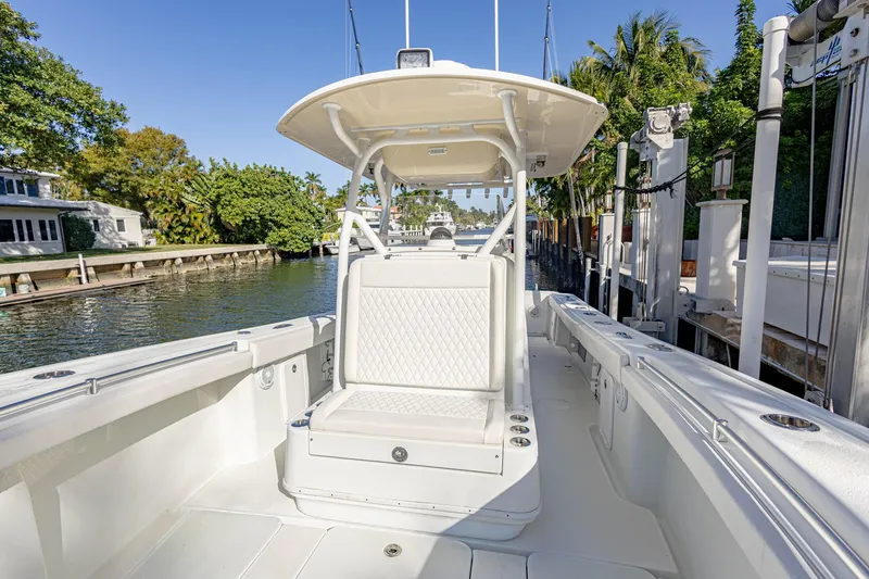 Slide: The Image of 2015 Yellowfin 32 Offshore boat interior with seating, docked by a scenic waterfront. - 6