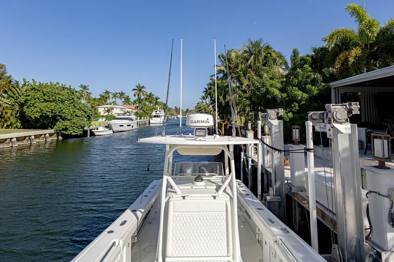 Slide: The Image of 2015 Yellowfin 32 Offshore boat docked in a scenic canal with palm trees. - 7