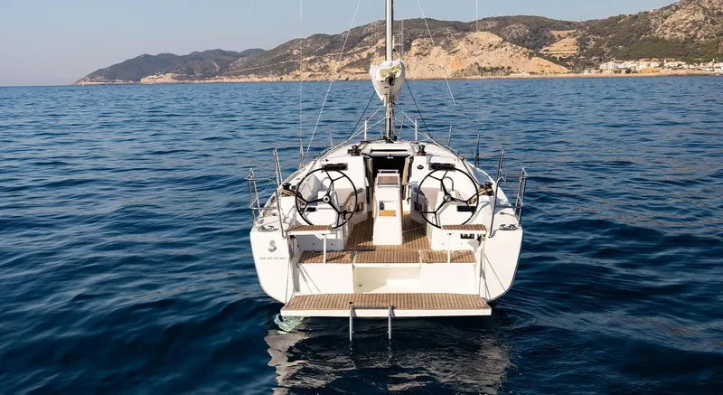 Slide: The Image of 2024 Beneteau Oceanis 34.1 sailboat on calm sea with scenic mountain backdrop. - 10