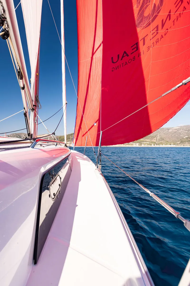 Slide: The Image of 2024 Beneteau Oceanis 34.1 sailboat with vibrant red sails on open water. - 6