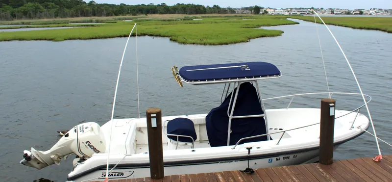 Slide: The Image of 1999 Boston Whaler Outrage 23 boat docked by a serene marshland. - 15