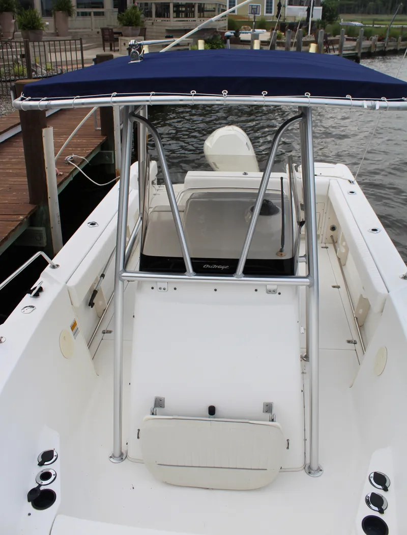 Slide: The Image of 1999 Boston Whaler Outrage 23 boat docked, featuring a blue T-top and center console. - 6