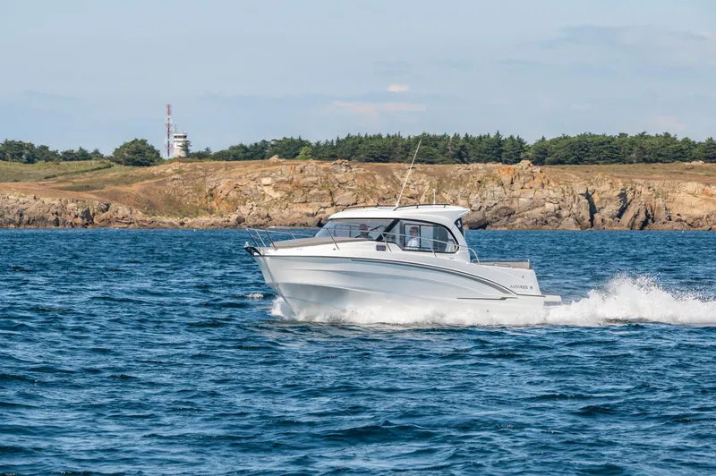 Slide: The Image of 2023 Antares 8 V2 boat cruising on the ocean near a rocky coastline. - 8