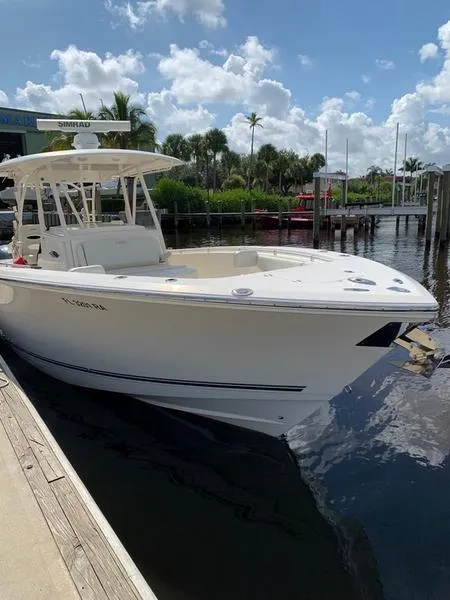 Slide: The Image of 2015 Cobia 344 Center Console boat docked at a marina on a sunny day. - 2