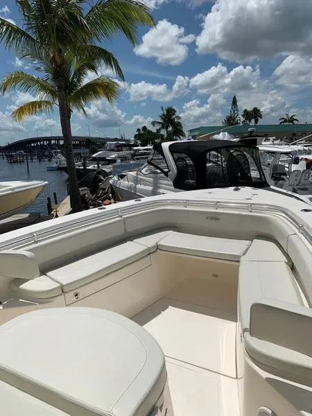 Slide: The Image of 2015 Cobia 344 Center Console boat docked at a marina under a sunny sky. - 3