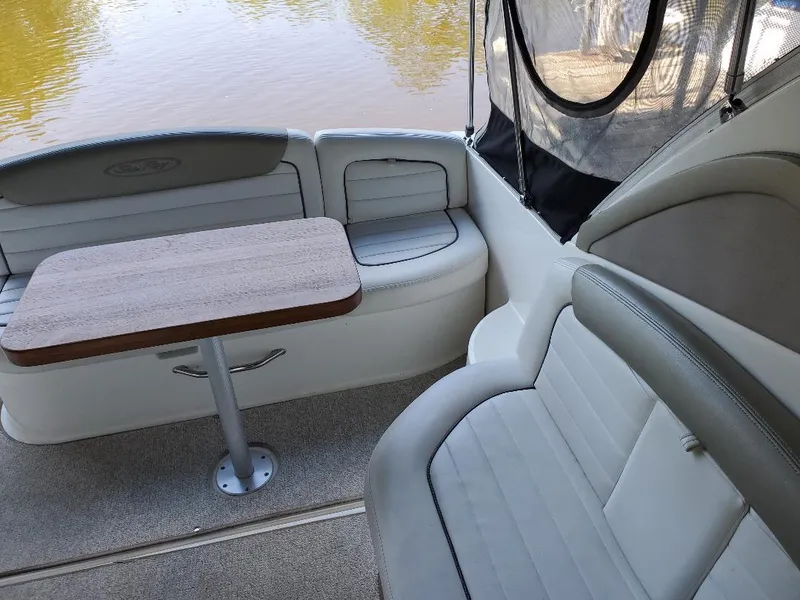 Slide: The Image of 2007 Sea Ray 290 Sundancer interior with seating and table, overlooking calm water. - 12