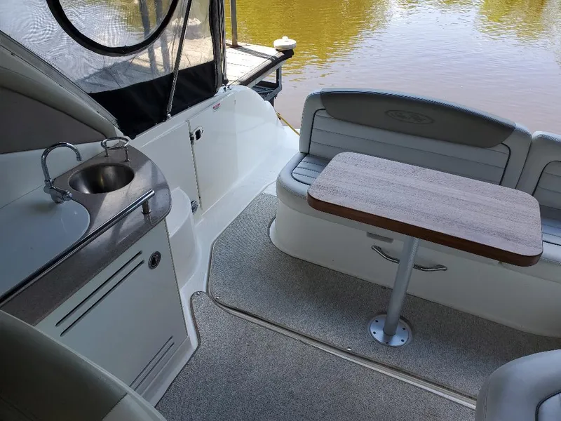 Slide: The Image of 2007 Sea Ray 290 Sundancer interior with seating, table, and sink by the water. - 30