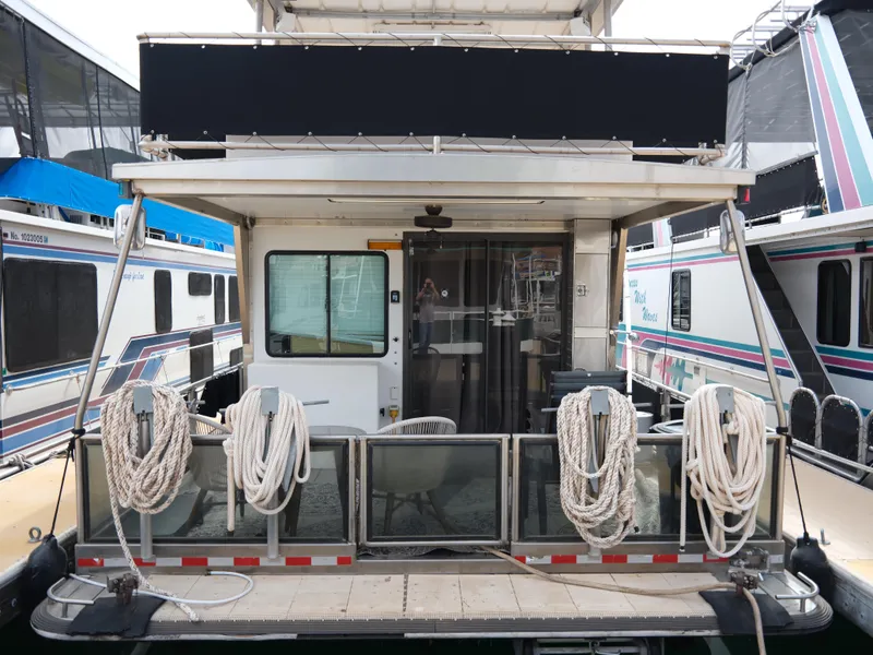 Slide: The Image of 1999 Custom 55x14 Stainless Houseboat docked with ropes and outdoor seating. - 2