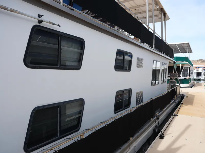 Slide: The Image of 1999 Custom 55x14 Stainless Houseboat docked, side view with multiple windows. - 21