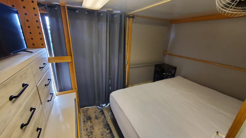 Slide: The Image of Interior bedroom of a 1999 Custom 55x14 Stainless Houseboat with bed, dresser, and curtains. - 3