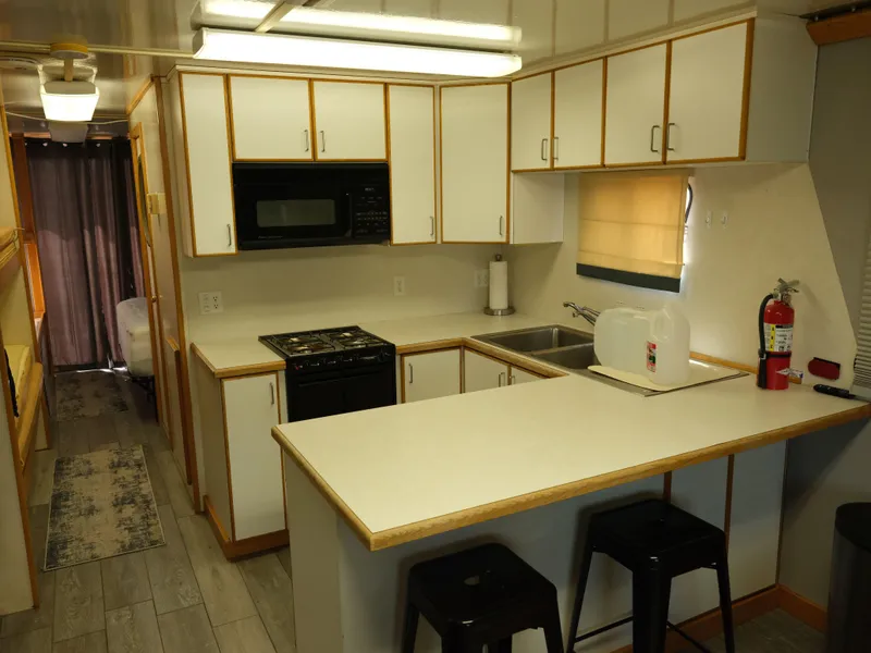 Slide: The Image of Modern kitchen in a 1999 Custom 55x14 Stainless Houseboat with white cabinets and black appliances. - 30
