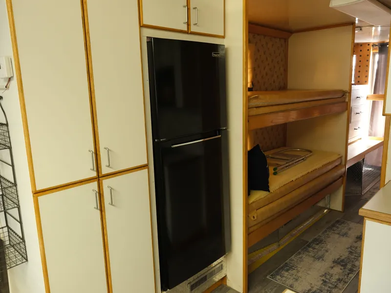 Slide: The Image of Interior of a 1999 Custom 55x14 Stainless Houseboat with bunk beds and a black refrigerator. - 31